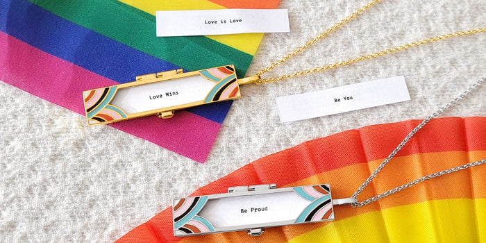 Two lockets placed on top of pride flags over a cream textured background